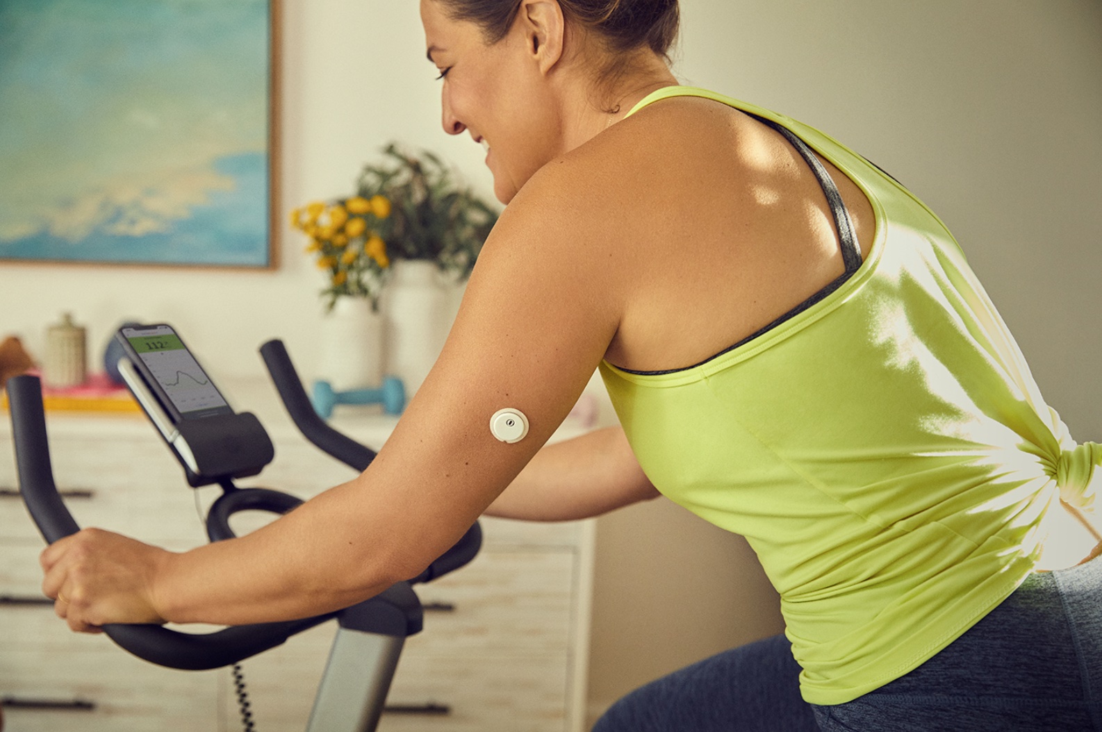 Woman on stationary bike wearing Freestyle Libre 3 CGM